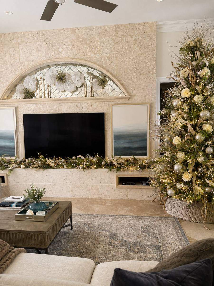 Living room Christmas tree with cream and gold ornaments beside a stone fireplace, styled by Light the Lights