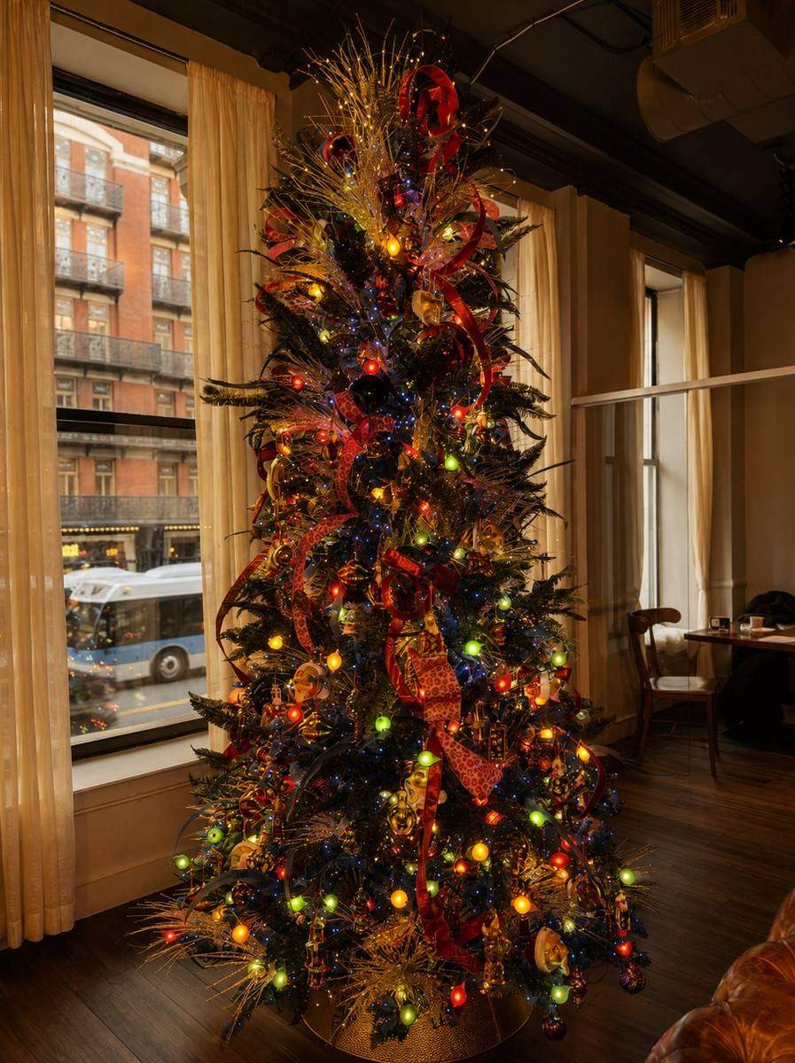 Jewel-tone Christmas tree with ribbon and ornaments beside a restaurant window, styled by Light the Lights