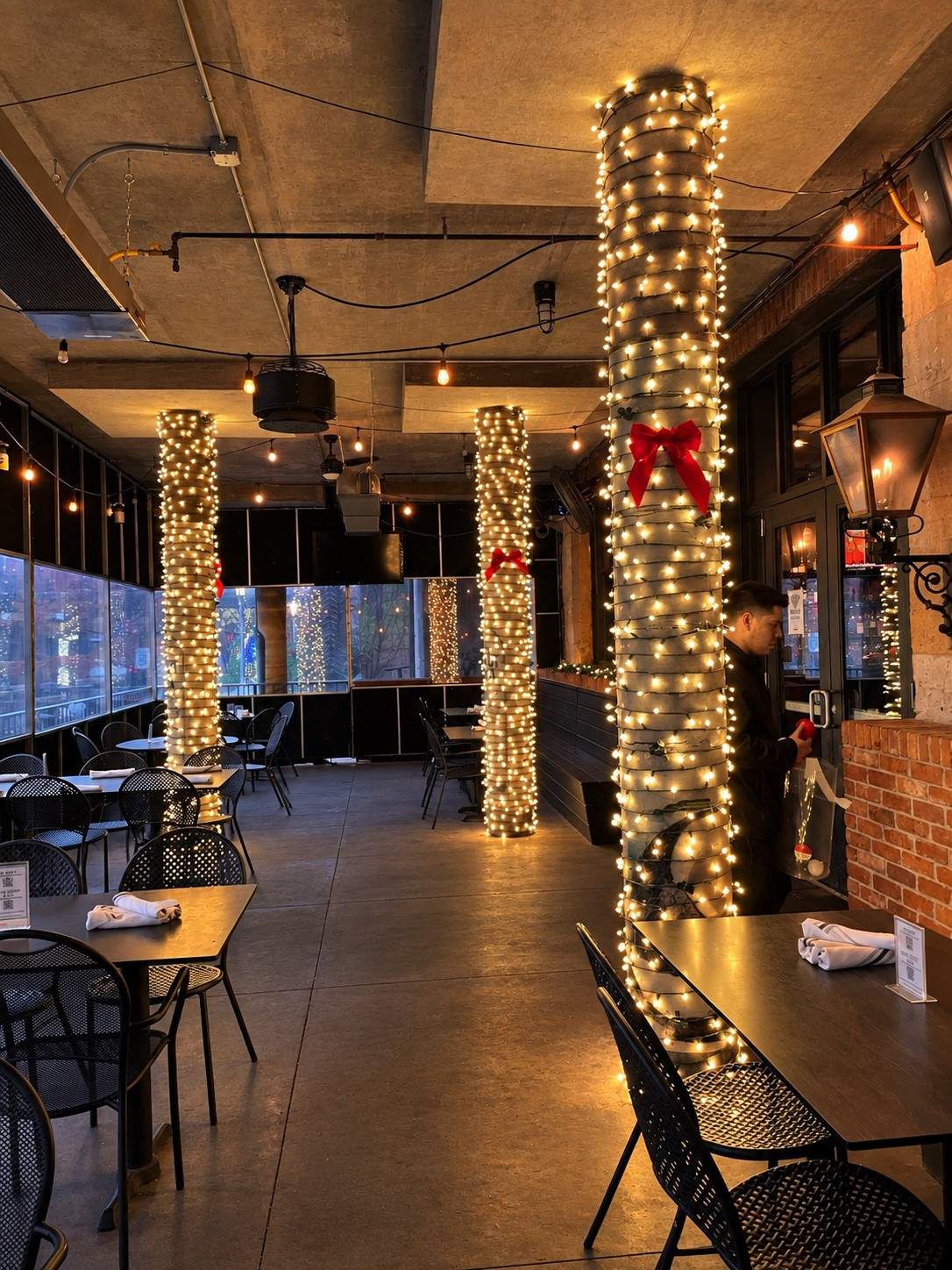 Restaurant interior columns wrapped in warm white lights with red bows